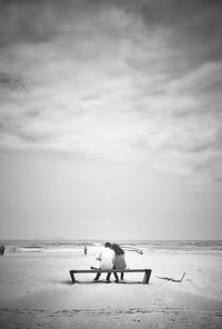 People sitting on beach against sky