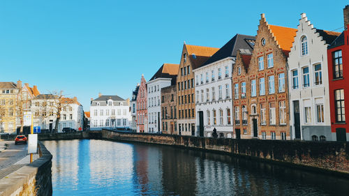 Canal amidst buildings against clear blue sky