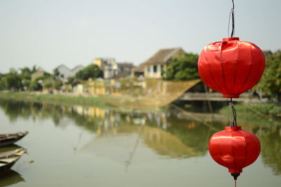 Close-up of red lanterns hanging over lake against sky