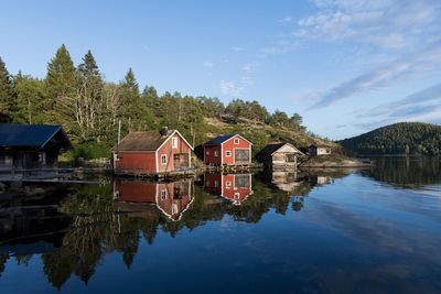 Reflection of trees and houses in lake against sky