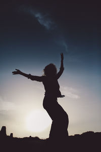 Low angle view of silhouette woman dancing against sky during sunset