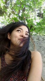 Close-up of young woman against trees