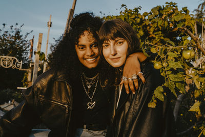 Smiling female friends with arm around in park on sunny day