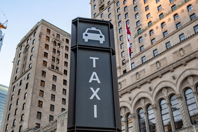 Low angle view of taxi sign against sky