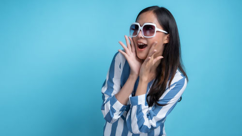 Young woman wearing sunglasses against blue background