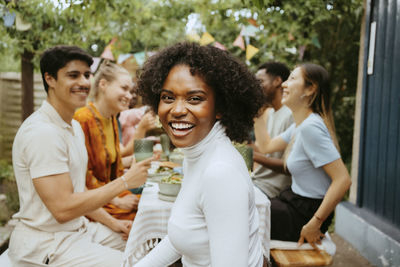 Side view portrait of happy woman with friends at dining table at dinner party