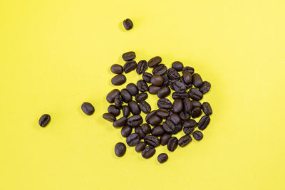 High angle view of coffee beans against yellow background