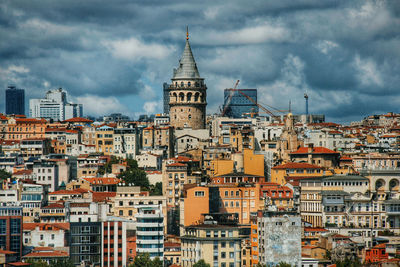 View of galata in city against cloudy sky