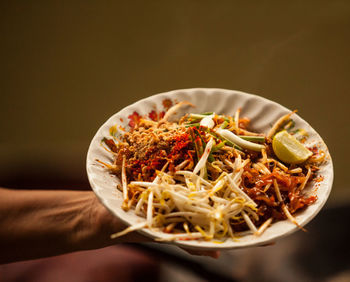 Close-up of hand holding noodles in bowl