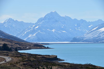 Scenic view of lake by snowcapped mountains against sky