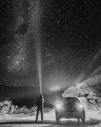 Rear view of man on illuminated street against sky at night