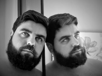 Reflection of thoughtful man with beard on mirror