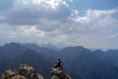 Man sitting on mountains against sky