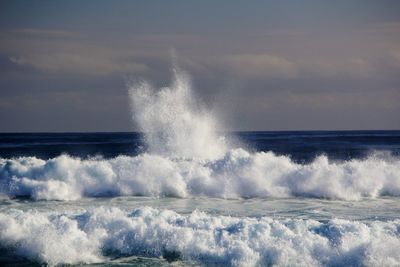 Waves splashing on sea against sky