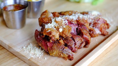 High angle close-up of pork served on cutting board at wooden table