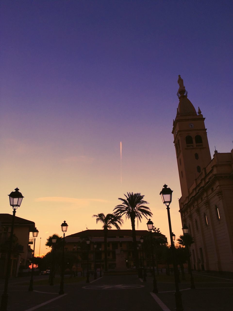 STREET BY BUILDINGS AGAINST SKY AT SUNSET