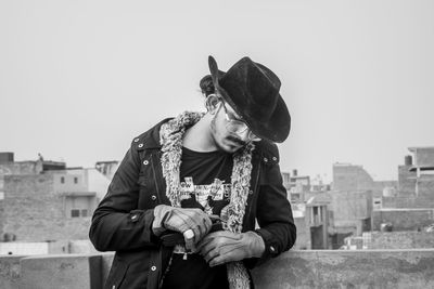 Young man wearing hat standing against town