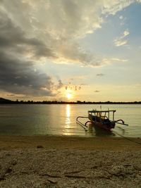 Boat moored on sea against sky during sunset