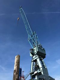 Low angle view of crane against blue sky