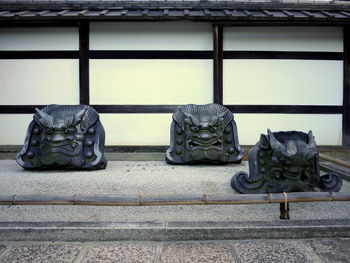 Group of three decorative roof tiles with faces of demons in a japanese garden