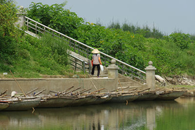 Man standing on footbridge over river against sky