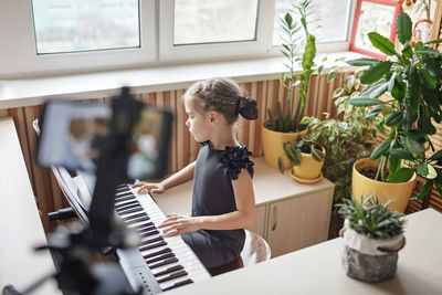 Side view of boy playing piano at home