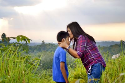 Couple kissing on field against sky