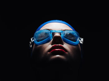 Portrait of man wearing sunglasses against black background