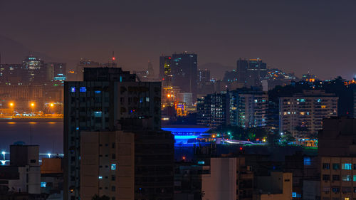 Illuminated buildings in city against sky at night