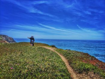 Rear view of man standing at beach against sky