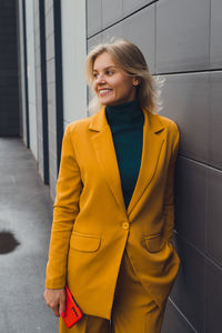 Portrait of young woman standing against wall