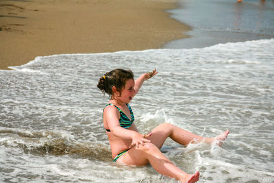 Rear view of woman sitting on beach