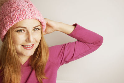 Portrait of smiling woman wearing knit hat against wall