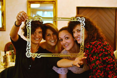 Portrait of smiling friends looking through picture frame