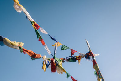 Low angle view of flags hanging against clear blue sky