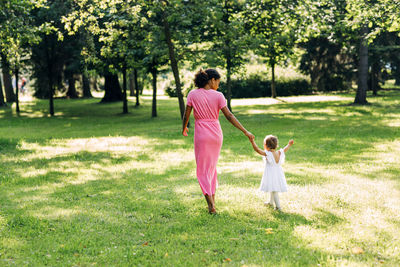 Rear view of mother and daughter on field