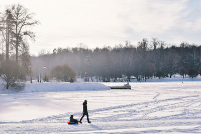 People on snow covered field against sky