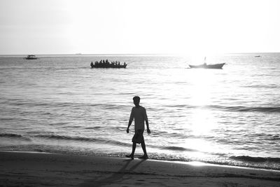 Silhouette man standing on beach against clear sky