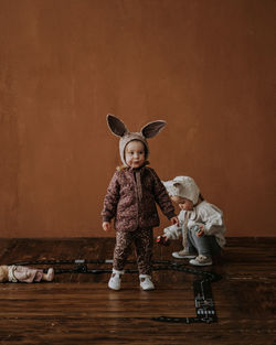 Full length of a boy standing on hardwood floor against wall