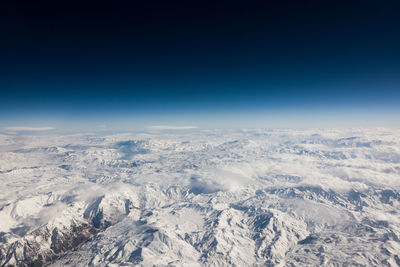 Aerial view of snowcapped mountains against clear blue sky