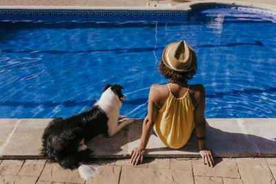 Rear view of woman sitting in swimming pool