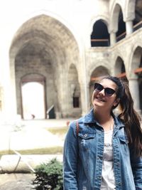 Young woman wearing sunglasses against built structure