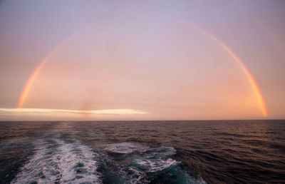 Scenic view of rainbow over sea against sky