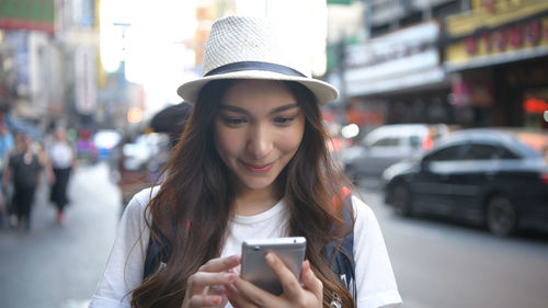 Portrait of young woman using smart phone on street