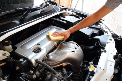 Cropped hand of man cleaning car engine