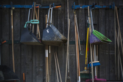 Mops hanging with dustpans on wooden wall