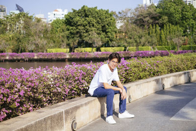 Full length of man sitting on purple flowering plants