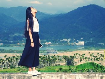 Woman standing on field against mountain range