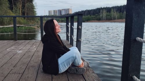 Woman sitting on pier by lake