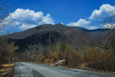 Road by mountains against sky